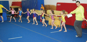Kindergym tots and parents start their warmups to the tune of "London Bridge"